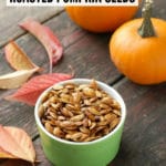 Roasted Pumpkin Seeds with powdered chipotle and small pumpkins in background with leaves