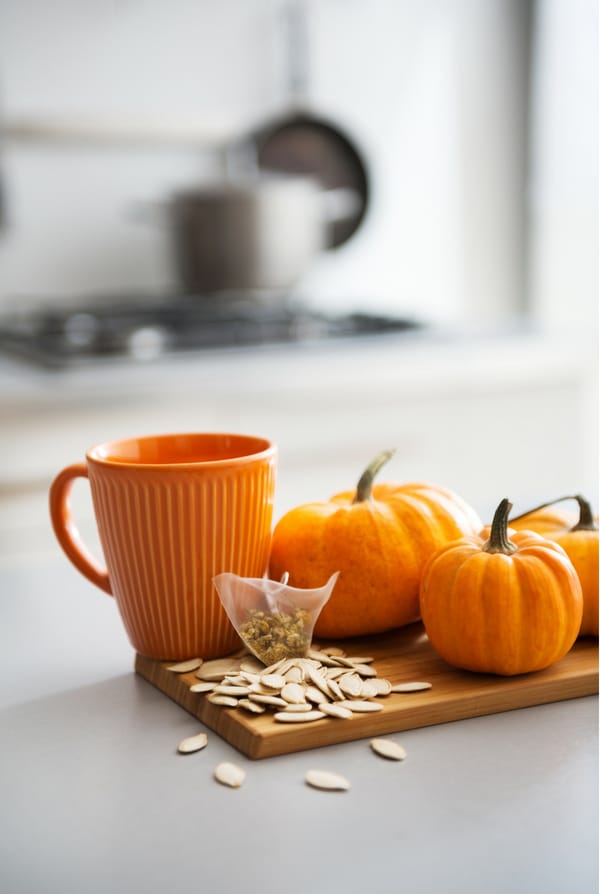 mini pumpkins, pumpkin seeds and orange mug on kitchen counter