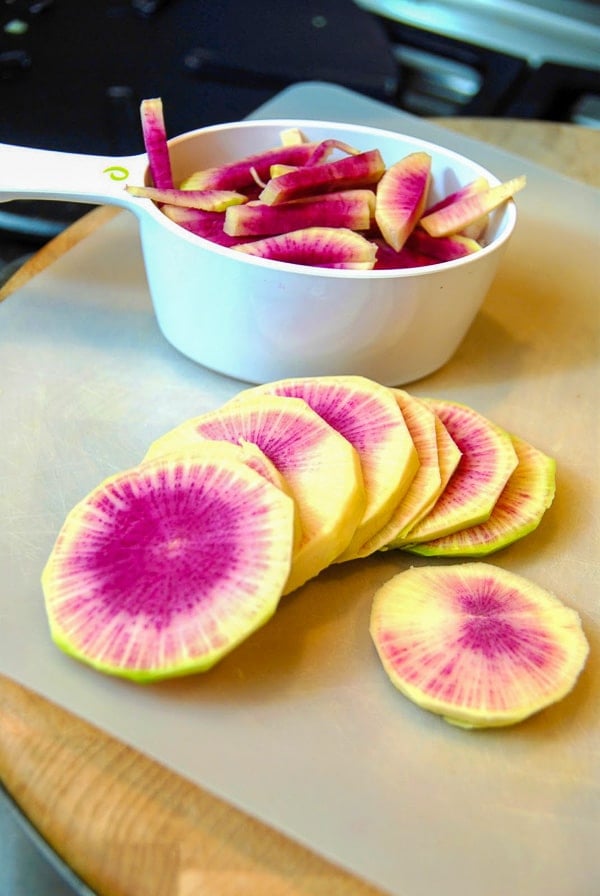 sliced Watermelon Radishes on a cutting board with some cut into sticks for making refrigerator pickles