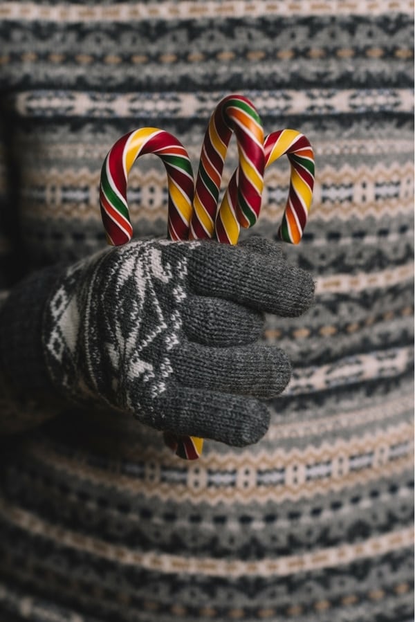 handful of candy canes with gray wool gloves 