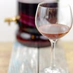 Wine goblet of homemade red wine vinegar with vinegar making glass jar in the background