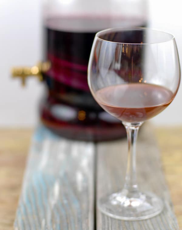 Wine glass with homemade red wine vinegar with vinegar container in the background