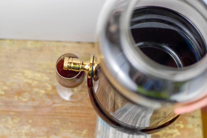 Homemade red wine vinegar drained into a wine glass with spigot