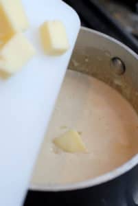 adding cubed cheese to sauce