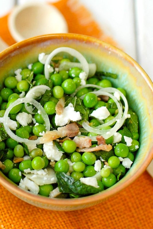 pea salad recipe with pancetta, goat cheese, shallots and mint in a bowl