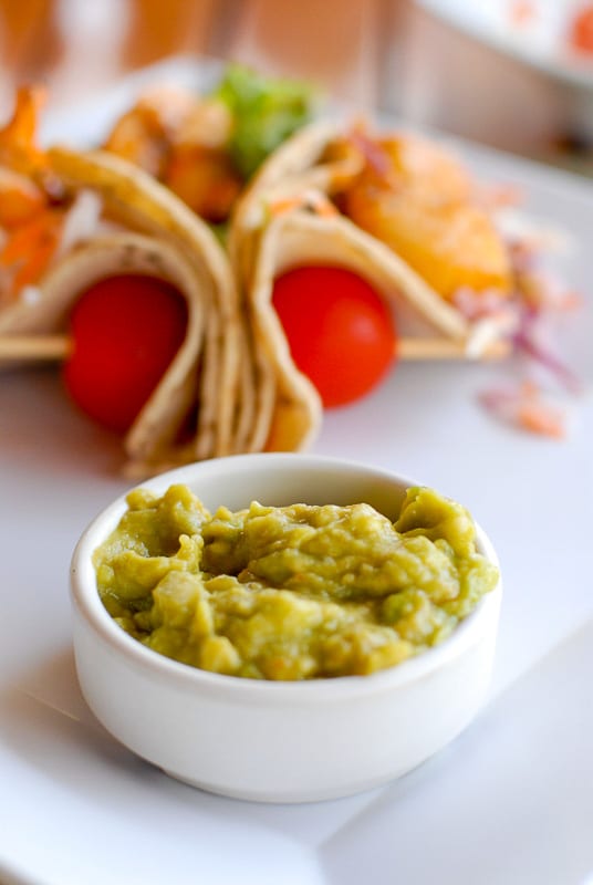 freshly made guacamole with fish tacos in background in Costa Rica