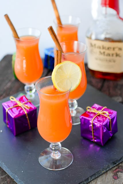 Warm holiday Wassail in hurricane glasses with cinnamon sticks and lemon slices 