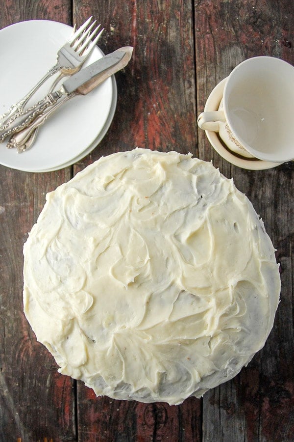 Whole Italian Cream Cake uncut with empty coffee cups and dessert plates