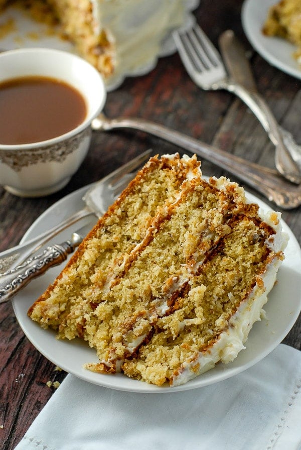 large slice of Italian Cream Cake with a cup of coffee in the background