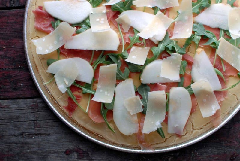 unbaked slice Pear Proscuitto Arugula Pizza in pizza pan