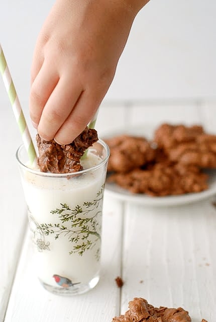 A person holding a cookie dipped in milk
