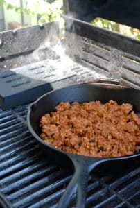 Chorizo in skillet on grill with smoker box