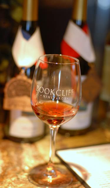 A close up of a wine glass, with Bottle and Red Wine