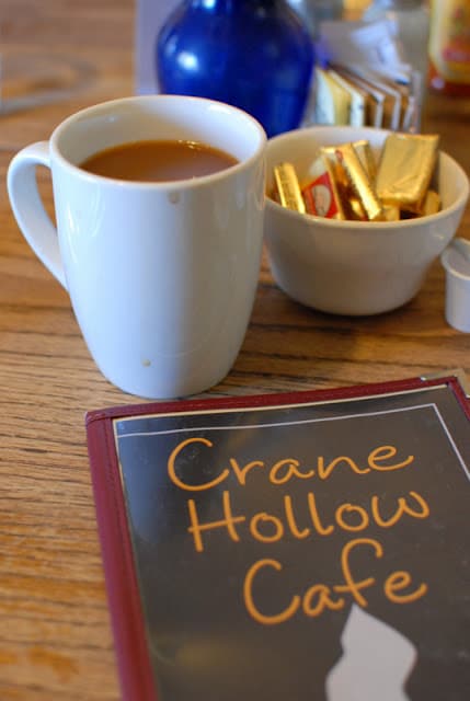 A cup of coffee on a table with menu