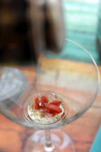 straining goji berry vodka martini into cocktail glass