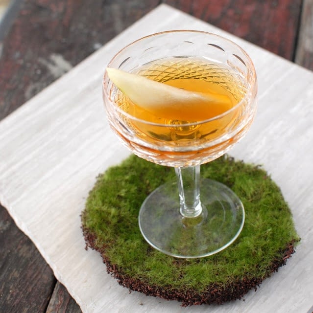 A glass of wine sitting on top of a wooden table, with Brandy