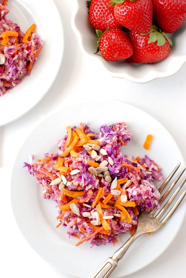 overhead view of carrot and cabbage slaw with Strawberry-Peach Balsamic Dressing and sunflower seeds on a white plate