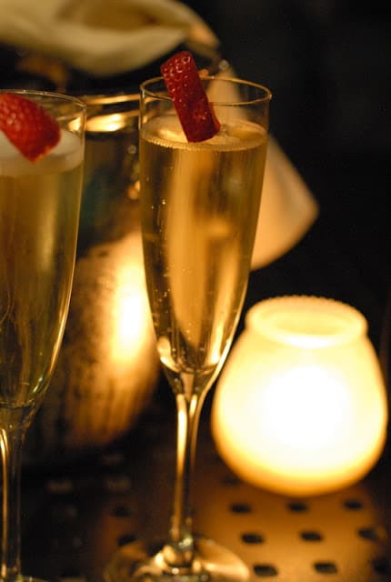 glasses of champagne with strawberry on rim in candlelight