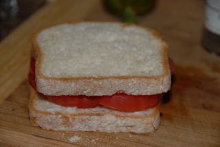 A cut in half sandwich sitting on top of a wooden cutting board, with Toast