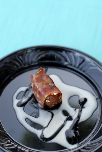 bacon wrapped date on black plate