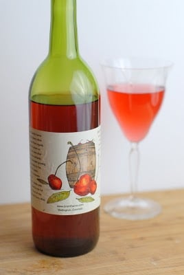 A bottle of wine and a glass of beer on a table, with Fruit