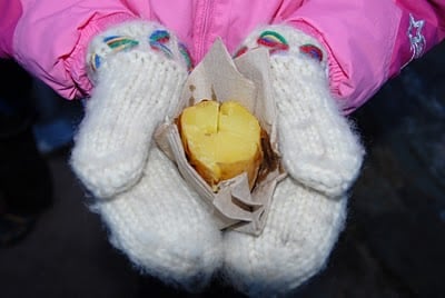 childs hands with mittens and cooked potato