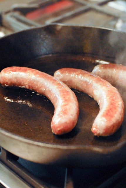 A close up of a metal pan on a stove, with Sausage and Cure Organic Farm