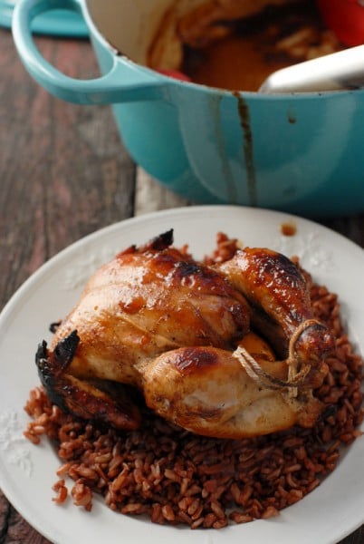 A bowl of food on a plate, with Glaze and Cornish game hen