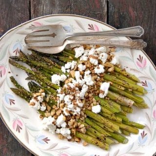 platter of Roasted Balsamic Asparagus with Goat Cheese and Toasted Walnuts on a weathered wood background