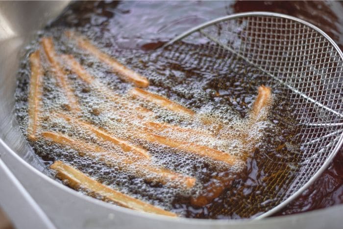 frying churros with strainer scoop