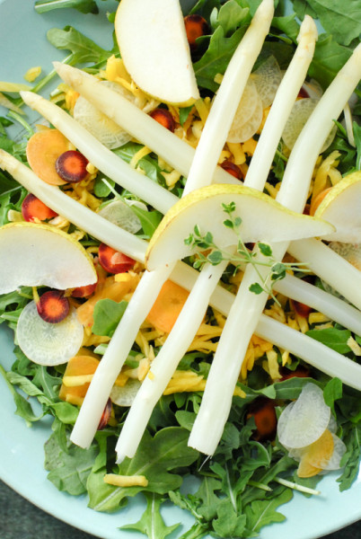 A bowl of salad on a plate with white asparagus