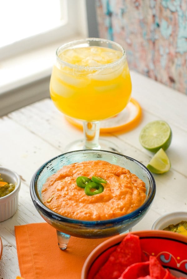 A plate of food and a glass of orange juice, with Salsa and Chile con queso