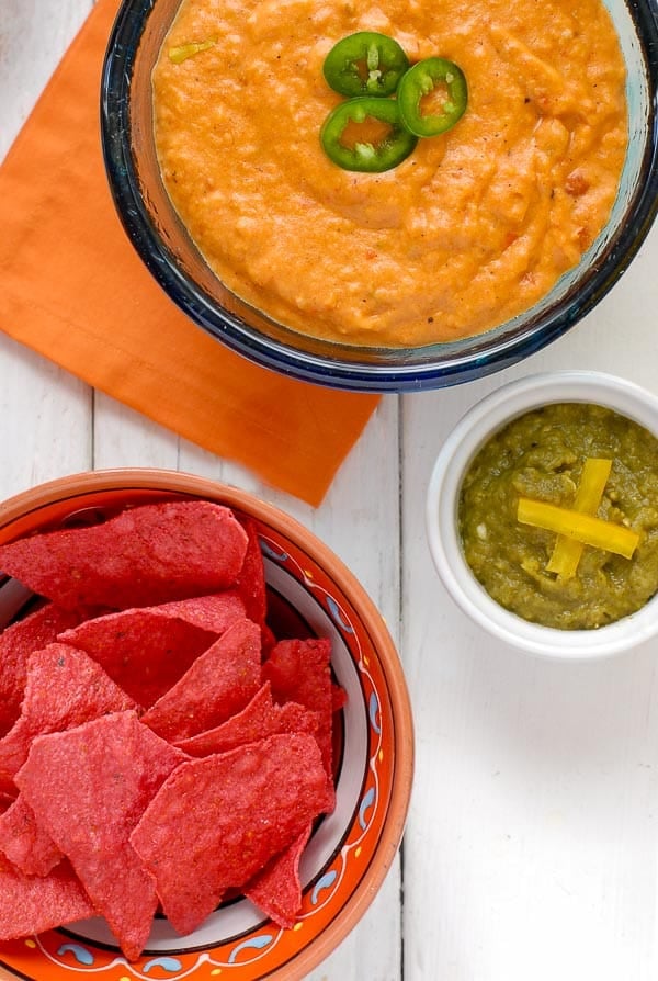 A bowl of food on a table, with Salsa and Chile con queso