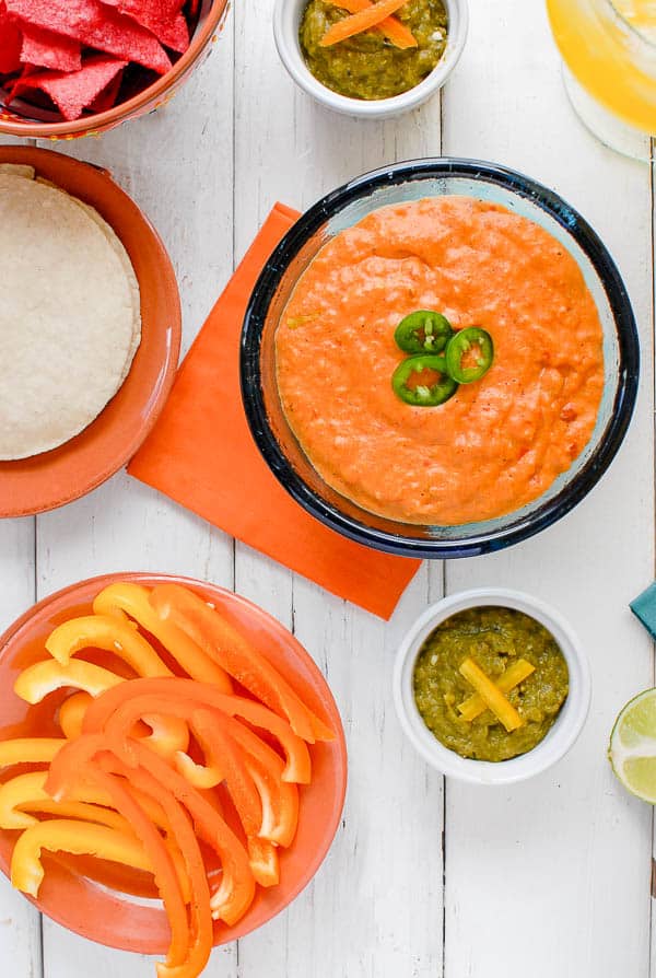 A bowl filled with different types of food on a table, with Salsa and Chile con queso