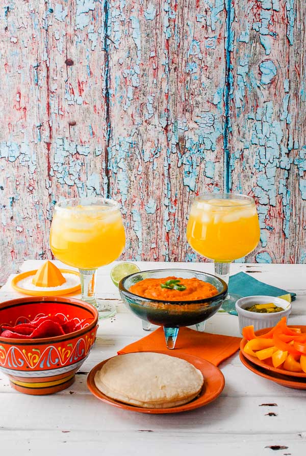 A plate of food and a glass of orange juice, with Salsa and Chile con queso