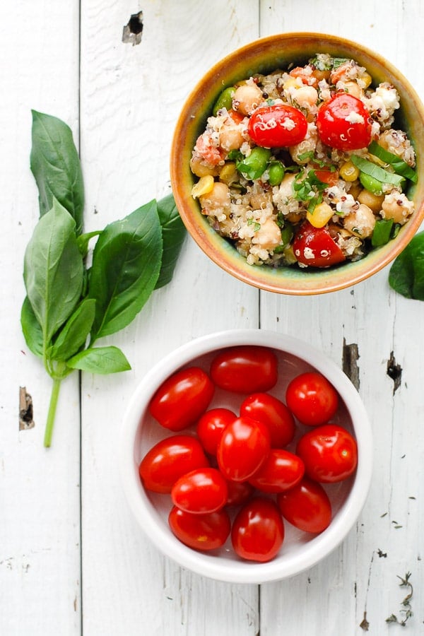 a bowl of Rainbow Quinoa Summer Salad and bowl of cherry tomatoes