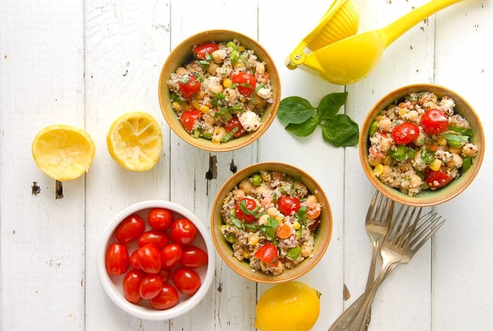 bowls of Rainbow Quinoa Summer Salad, tomatoes, lemons and juicer