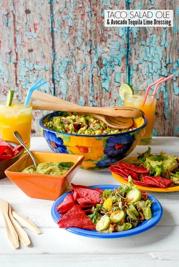 Taco Salad Ole with Avocado Tequila Lime Dressing in large bowl with flowers and on an individual plate with red corn chips