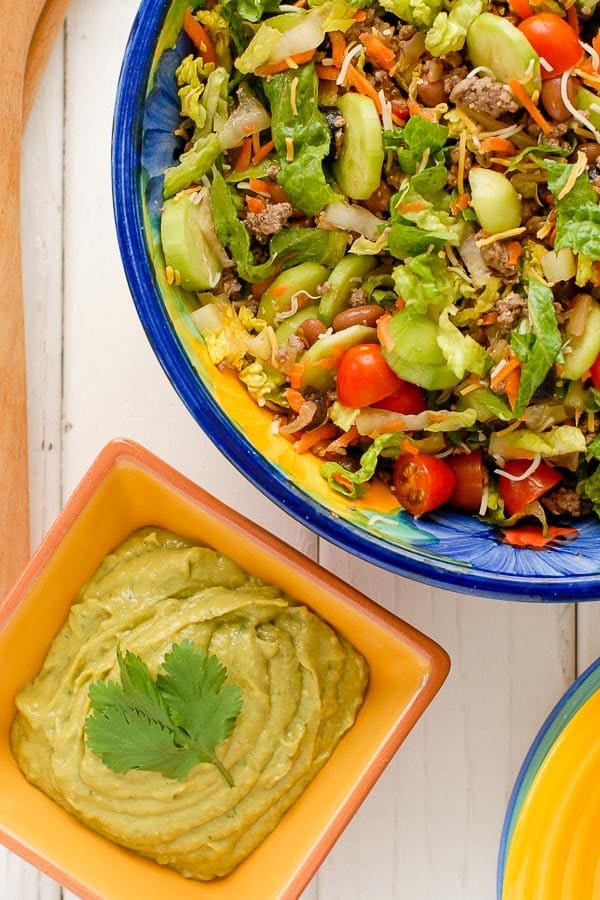 Taco Salad Ole in a colorful large bowl with Avocado Tequila Lime Dressing in a smaller orange bowl