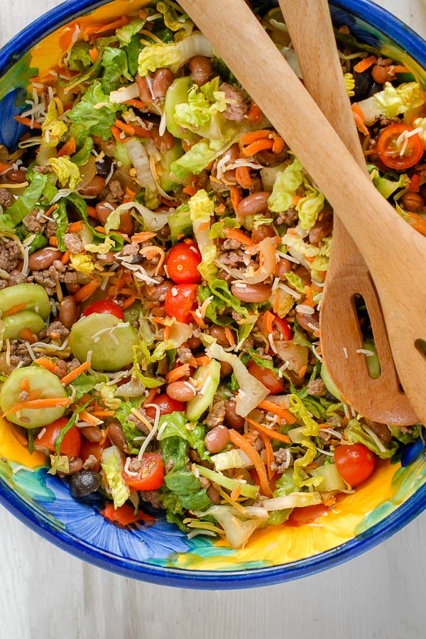 Colorful bowl of Taco Salad Ole with wooden salad servers