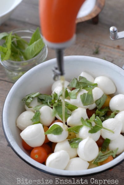 pouring olive oil onto caprese salad