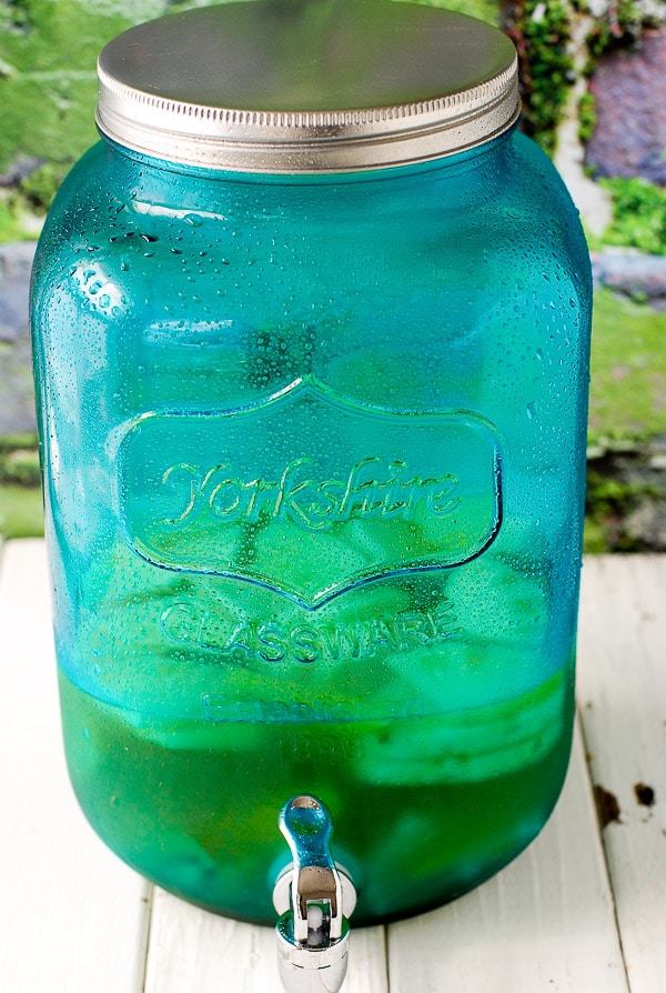 Blue glass infusing jar with silver spigot filled with Tropical Fruit Sangria 