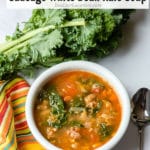 Peppery Sausage White Bean Kale soup in a white bowl with kitchen towel