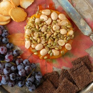 Baked Brie, Maple-Pumpkin Butter, Honey, Marcona Almonds, Pepitas with knife