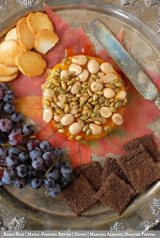 Baked Brie, Maple-Pumpkin Butter, Honey, Marcona Almonds, Pepitas with knife