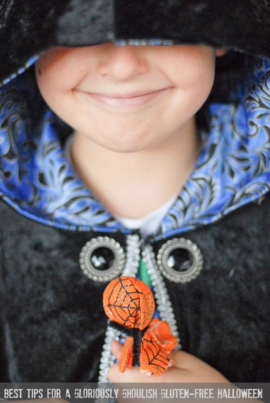 child in a cloak holding a halloween sucker