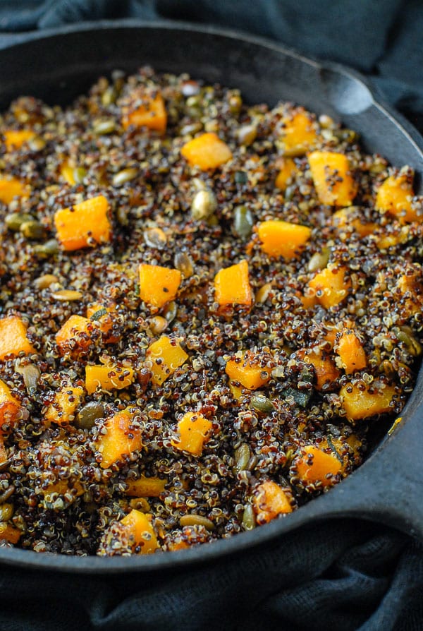 cast iron skillet of black quinoa in sage brown butter sauce with butternut squash