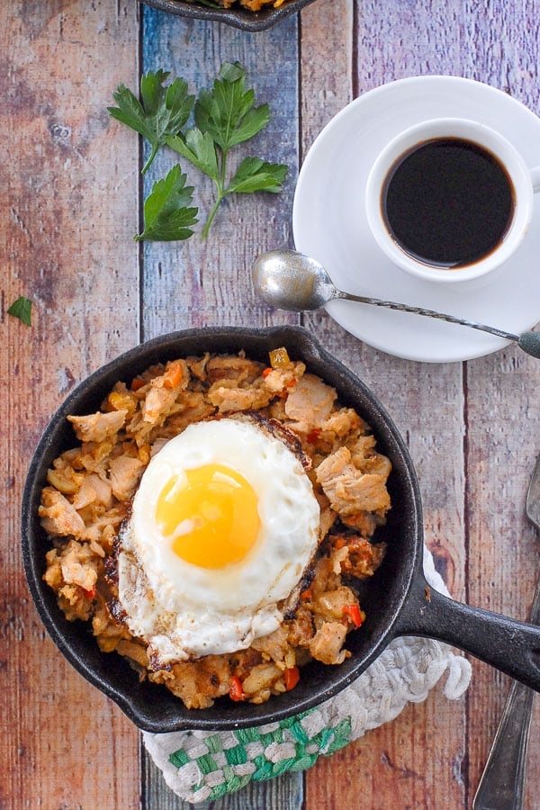 mini skillet of turkey hash with a fried egg on top and coffee cup