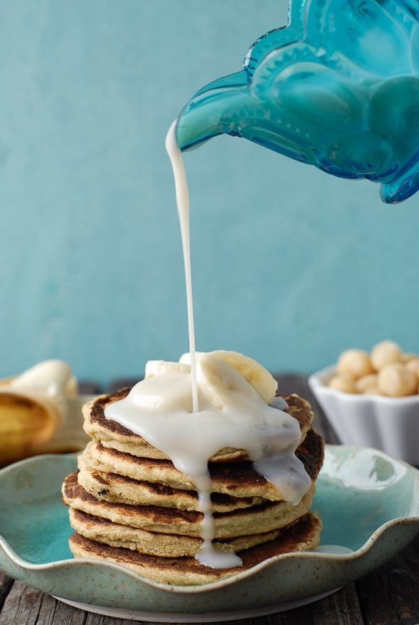 Banana-Macadamia Nut Pancakes with Coconut Syrup with pouring syrup