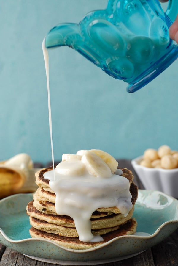 Syrup pouring over Banana-Macadamia Nut Pancakes 